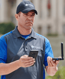 Installer with signal meter locates best signal strength spot for outside antenna.